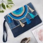 Aegean Boho Bag χειροποίητο τσαντάκι χειρός από τζιν ύφασμα με πλεκτό ματόχαντρο, φούντες και φερμουάρ