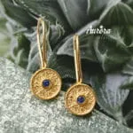 Τα Blue Orbit Earrings είναι ένα εκλεπτυσμένο κόσμημα που αποπνέει διαχρονική κομψότητα και σύγχρονη αισθητική. Κατασκευασμένα από ασήμι 925 και επιχρυσωμένα με λαμπερή, ζεστή απόχρωση χρυσού, διαθέτουν λεπτεπίλεπτο γαντζάκι που αγκαλιάζει απαλά το αυτί, χαρίζοντας άνεση και αριστοκρατική κίνηση. Ο στρογγυλός δίσκος των 9mm με τη διακριτική, ανάγλυφη υφή δημιουργεί ένα παιχνίδι φωτός που αναδεικνύει τη βαθιά μπλε πέτρα στο κέντρο — μια «τροχιά» χρώματος που μαγνητίζει το βλέμμα. Η αντίθεση του χρυσού με το έντονο μπλε προσδίδει χαρακτήρα και φινέτσα, καθιστώντας τα ιδανικά τόσο για καθημερινές εμφανίσεις με στιλ όσο και για πιο ιδιαίτερες περιστάσεις. Ένα κόσμημα που ισορροπεί ανάμεσα στη διακριτικότητα και την πολυτέλεια — μια μικρή, φωτεινή λεπτομέρεια που ολοκληρώνει κάθε σύνολο με αέρα υψηλής αισθητικής. Χαρακτηριστικά: Υλικό: Ασήμι 925 Φινίρισμα: Επιχρυσωμένο Διάμετρος δίσκου: 9mm Πέτρα: Μπλε Κούμπωμα: Γαντζάκι